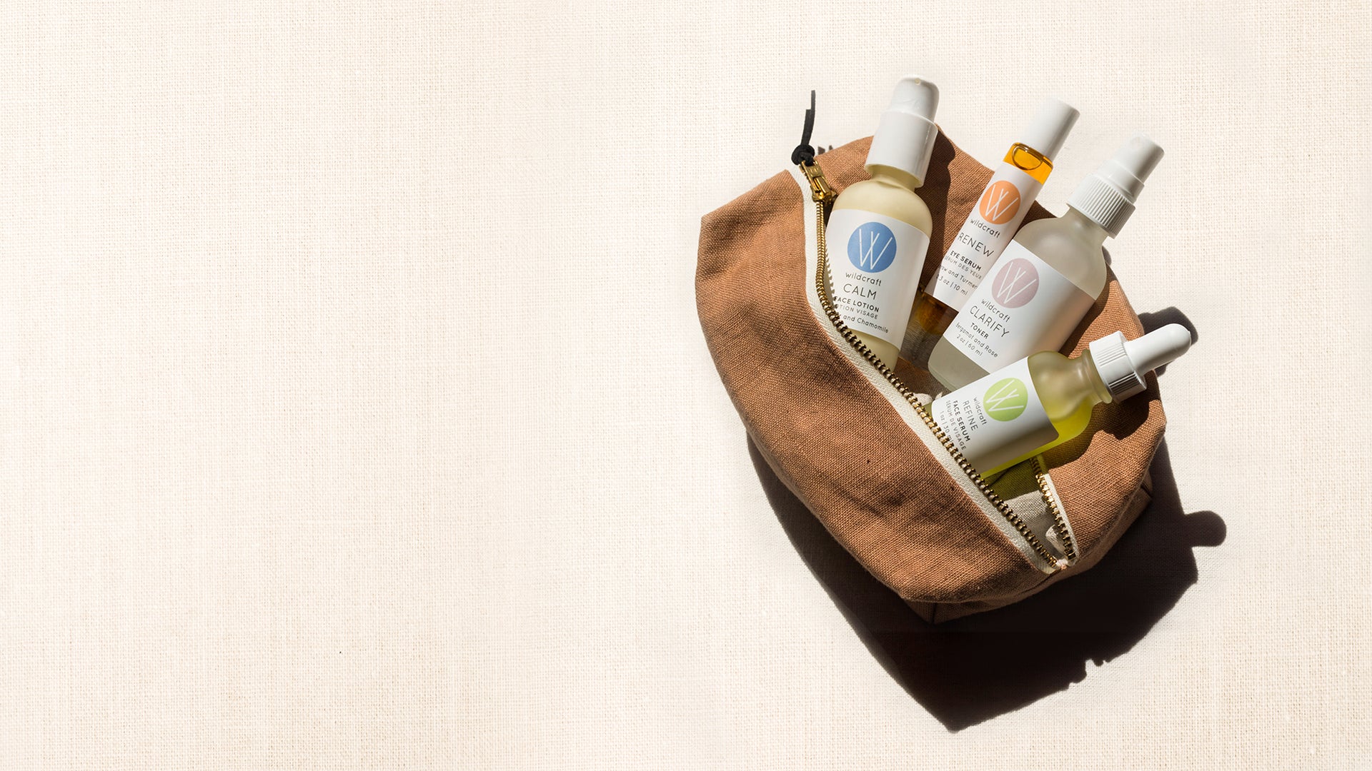 Wildcraft calm face lotion, toner, refine face serum, and eye serum in open make up bag on textured back drop